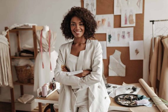 beautiful-curly-brunette-dark-skinned-fashion-designer-poses-office-leans-table