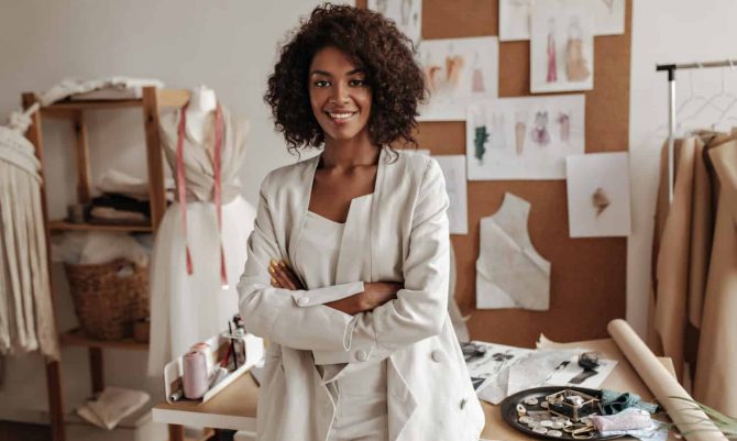 beautiful-curly-brunette-dark-skinned-fashion-designer-poses-office-leans-table